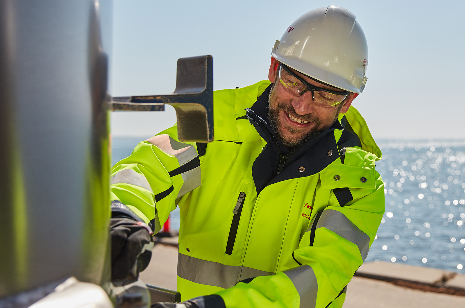 smiling man working on big metal machine