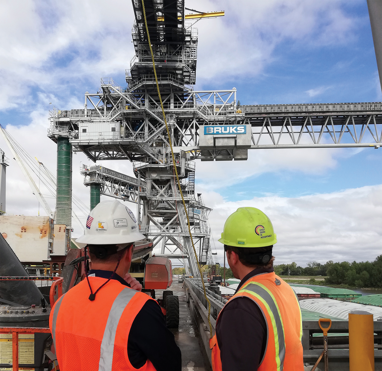 Two people standing and looking at the Bruks Siwertell shiploader.